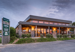 Huttopia Les Falaises camping in Normandië, Frankrijk, verlicht paviljoen bij avondschemer.