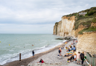 Bezoekers ontspannen op het kiezelstrand bij de kliffen van Huttopia Les Falaises, Normandië, Frankrijk.