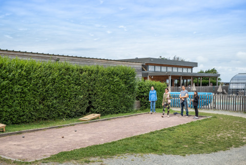 Familia jugando petanca en Huttopia Les Falaises - Normandie, un parque vacacional en Normandía, Francia.