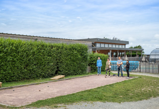 Familie spielt Boule auf dem Gelände von Huttopia Les Falaises - Normandie in der Normandie, Frankreich.