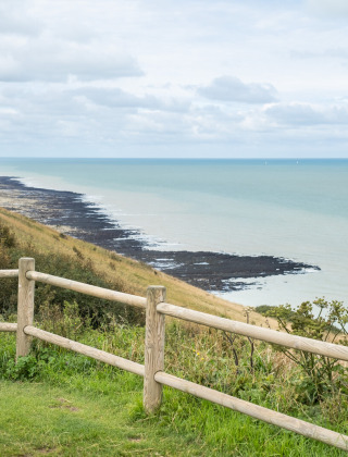 Dos niños miran el paisaje costero cerca de Saint-Pierre-en-Port, Normandía, Francia, en un día nublado.
