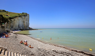 Playa de guijarros con bañistas junto a los acantilados de Saint-Pierre-en-Port, Normandía, Francia.