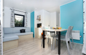 Zona de estar moderna en Cottage Prestige de Camping Seasonova Les 7 Iles con paredes azules y mesa de comedor.
