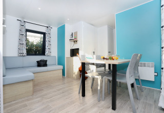 Zona de estar moderna en Cottage Prestige de Camping Seasonova Les 7 Iles con paredes azules y mesa de comedor.