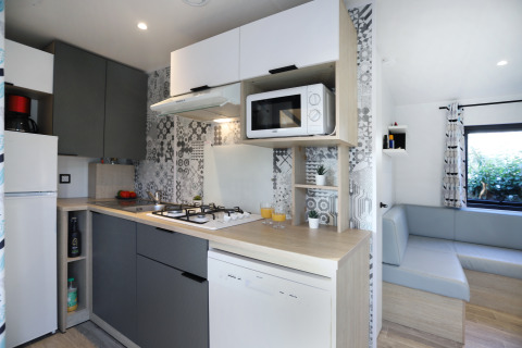 Modern kitchen of a Cottage Prestige cabin at Camping Seasonova Les 7 Iles in France, featuring sleek decor.