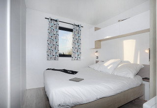 Bright, modern bedroom of Cottage Prestige at Camping Seasonova Les 7 Iles in France, featuring a double bed.