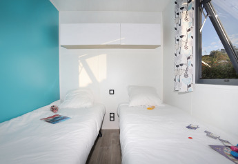 To enkeltsenge med hvidt sengetøj i et lyst værelse med blå væg, vindue og moderne skab i Cottage Prestige.