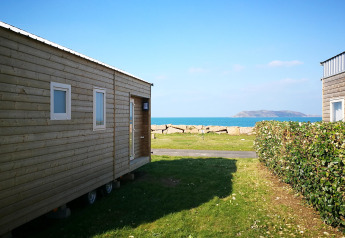 View from a Tiny House at Camping Seasonova Les 7 Iles in France with ocean, sky, and island in background.
