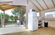 Vista interior de la cabaña Eco Lodge en Camping Seasonova Les 7 Iles, Francia, con cocina y terraza cubiertas.