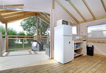 Vista interna della Eco Lodge al Camping Seasonova Les 7 Iles in Francia, con cucina e terrazza coperta.