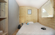 Interno di una cabina in legno all’Eco Lodge, Camping Seasonova Les 7 Iles, Francia, con letto e finestra.