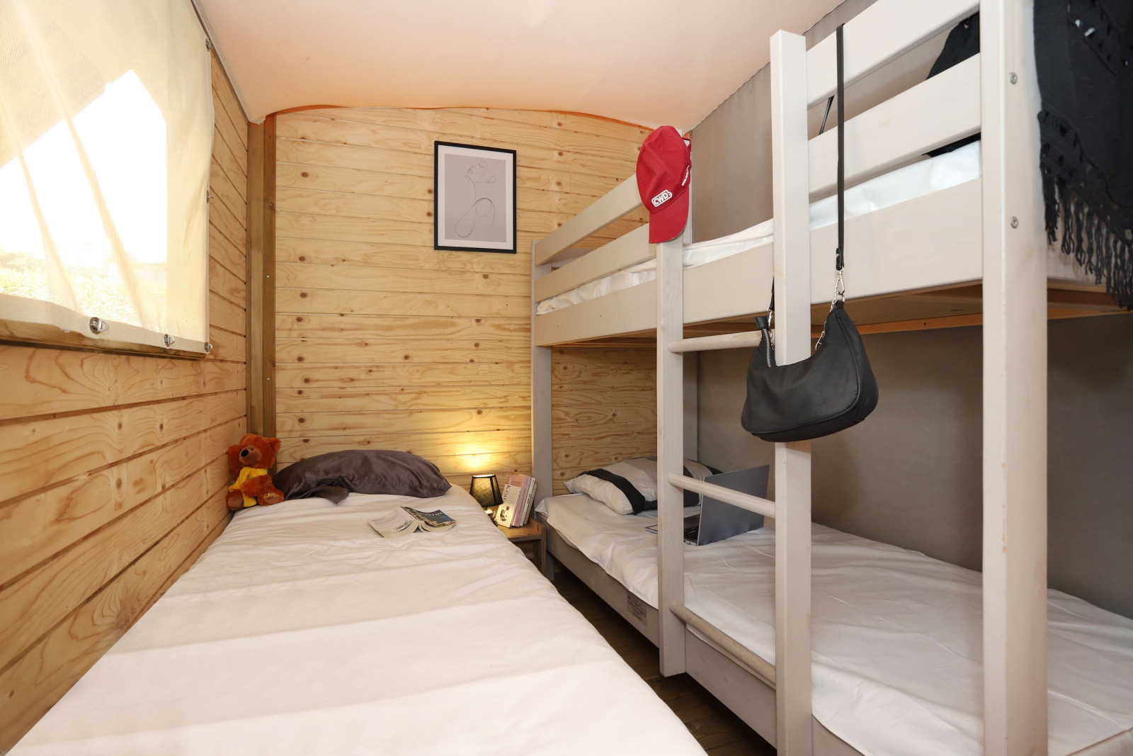 Slaapkamer in de Eco Lodge bij Camping Seasonova Les 7 Iles, Frankrijk, met stapelbedden en houten wanden.