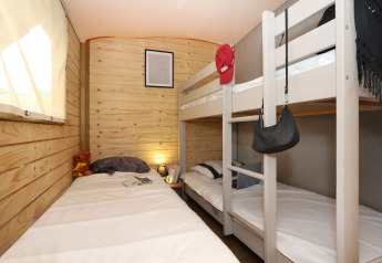 Dormitorio de la Eco Lodge en Camping Seasonova Les 7 Iles, Francia, con literas y paredes de madera.