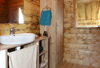 Baño rústico de madera con lavabo y toalla azul en Eco Lodge, Camping Seasonova Les 7 Iles, Francia.
