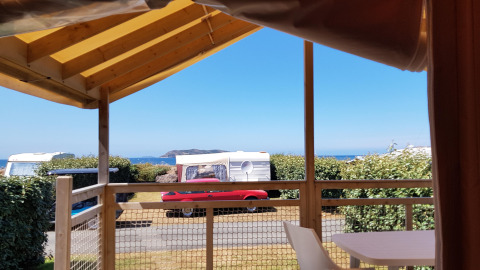 Blick von einer Eco Lodge bei Camping Seasonova Les 7 Îles in Frankreich mit Wohnwagen und Meer im Hintergrund.