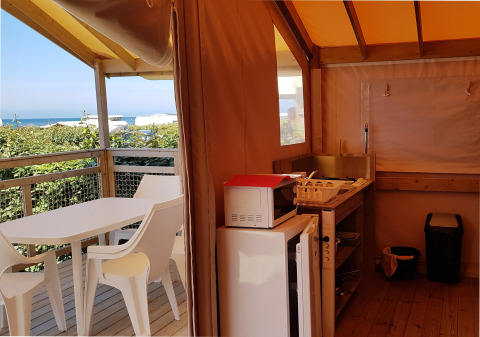 Vista interior de Eco Lodge en Camping Seasonova Les 7 Iles en Francia, con vistas al mar al fondo.