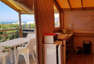 Vista interior de Eco Lodge en Camping Seasonova Les 7 Iles en Francia, con vistas al mar al fondo.