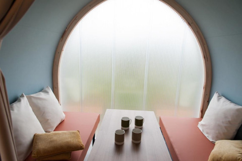 Interior de la tienda safari Coco Sweet en Camping Seasonova Les 7 Iles en Francia con asientos y tazas.