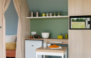 Kitchen area inside a Coco Sweet safari tent at Camping Seasonova Les 7 Iles in France with a microwave.