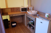 Angolo cottura compatto con piano in legno, lavello, mini frigo e microonde in Ecolodge Pmr in Francia.