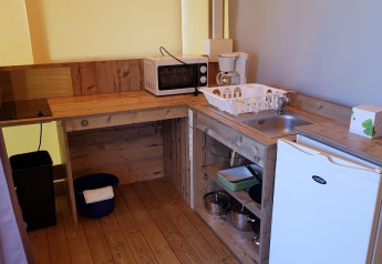 Compact kitchen corner with wooden counter, sink, mini fridge, microwave, and coffee maker at Ecolodge Pmr.
