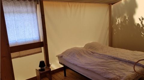 Dormitorio en Ecolodge PMR en Camping Seasonova Les 7 Iles, Francia, con cama y decoración de madera.