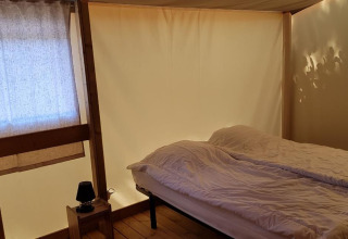Dormitorio en Ecolodge PMR en Camping Seasonova Les 7 Iles, Francia, con cama y decoración de madera.