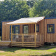 Moderne chalet Cottage Prestige med træbeklædning og veranda i naturskønt, solrigt område med træer.