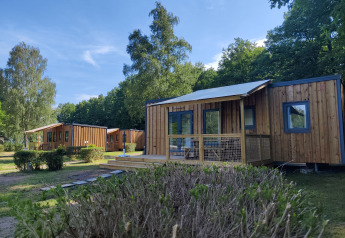 Foto del Cottage Prestige al Camping Seasonova Les Vosges du Nord con chalet in legno e vegetazione.