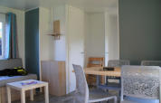 Interno luminoso del Cottage Prestige al Camping Seasonova Les Vosges du Nord, Francia, con tavolo da pranzo.