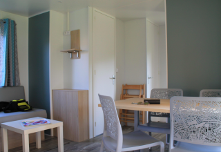 Lyst interiør af Cottage Prestige på Camping Seasonova Les Vosges du Nord med spisebord og sofa.