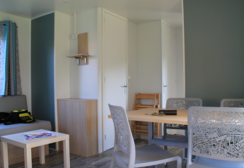 Lyst interiør af Cottage Prestige på Camping Seasonova Les Vosges du Nord med spisebord og sofa.