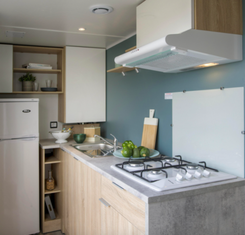 Moderne Küchenzeile im Cottage Prestige auf Camping Seasonova Les Vosges du Nord mit Gasherd und Kühlschrank.
