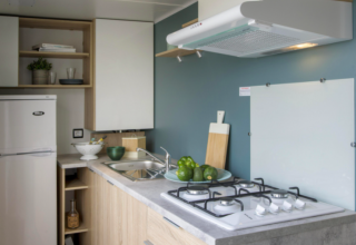 Moderne Küchenzeile im Cottage Prestige auf Camping Seasonova Les Vosges du Nord mit Gasherd und Kühlschrank.