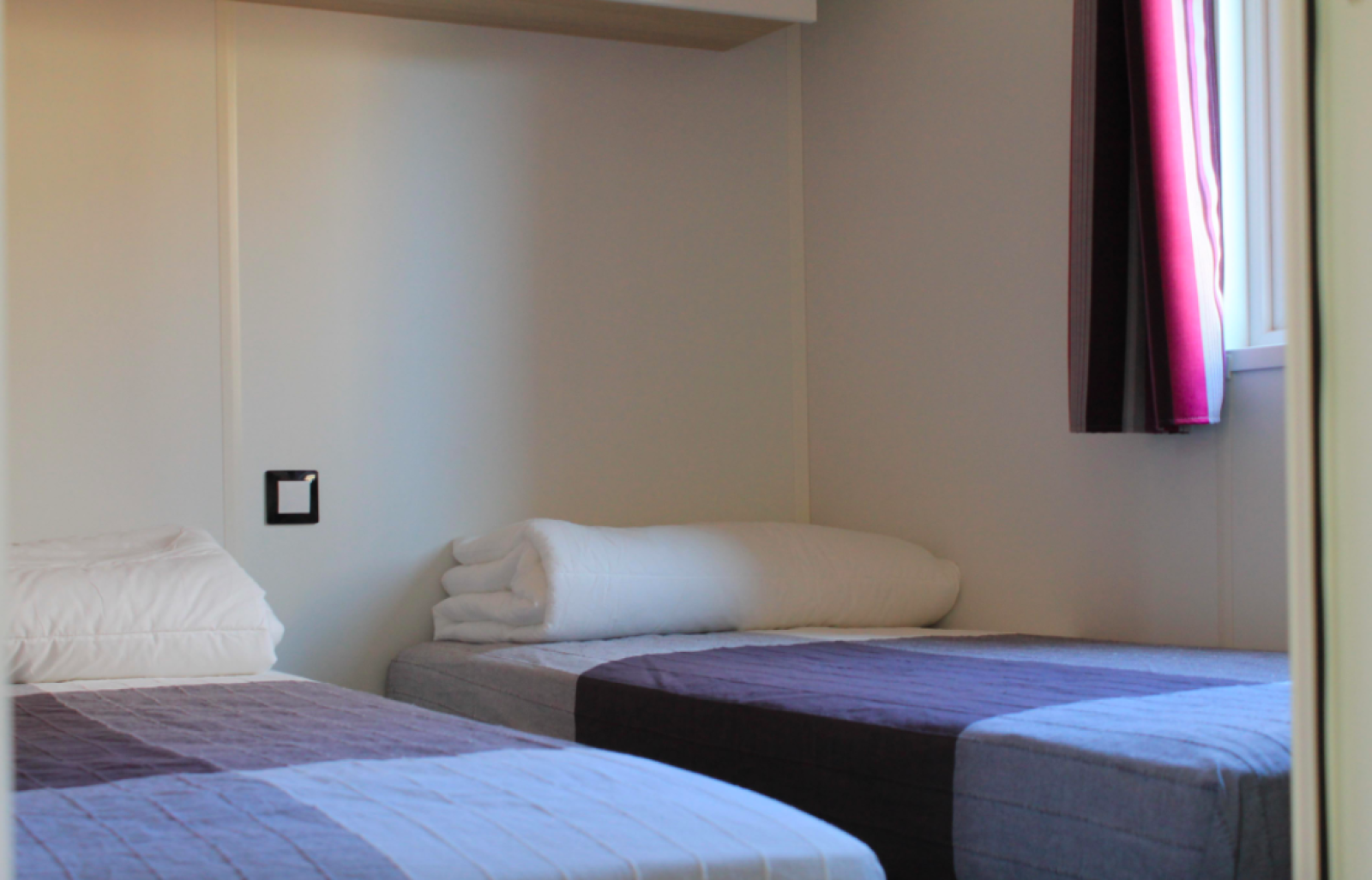 Twee eenpersoonsbedden in een lichte kamer in Cottage Prestige bij Camping Seasonova Les Vosges du Nord, Frankrijk.