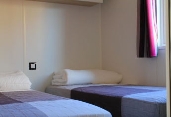 Due letti singoli in una stanza luminosa al Cottage Prestige presso Camping Seasonova Les Vosges du Nord, Francia.