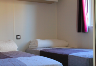 Zwei Einzelbetten in einem hellen Zimmer im Cottage Prestige auf dem Camping Seasonova Les Vosges du Nord in Frankreich.