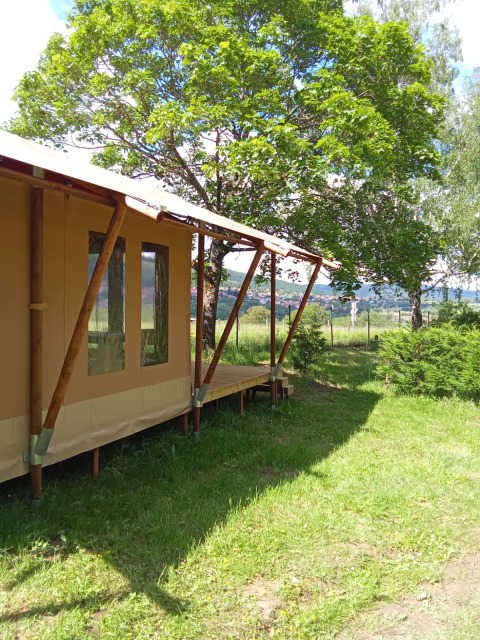 Safari-teltet Wood Lodge ved Camping Seasonova Les Vosges du Nord i Frankrig på en solrig dag med grønne træer.