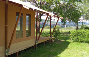 Safari tent Wood Lodge at Camping Seasonova Les Vosges du Nord in France, surrounded by lush green trees.
