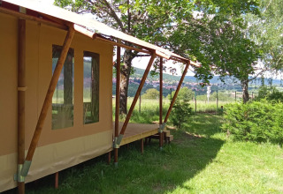 Tienda safari Wood Lodge en Camping Seasonova Les Vosges du Nord en Francia, rodeada de árboles verdes.