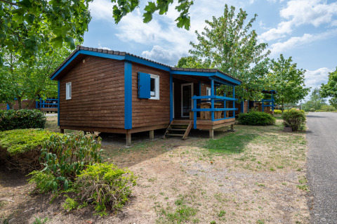 Accogliente chalet in legno con rifiniture blu immerso nel verde, ideale per un’esperienza di glamping.