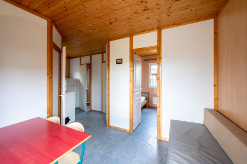 Interieur van een houtbeklede chalet bij Camping Seasonova Les Vosges du Nord met tafel en zitbank.