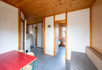 Interno di uno chalet con pannelli in legno al Camping Seasonova Les Vosges du Nord, tavolo e divano.