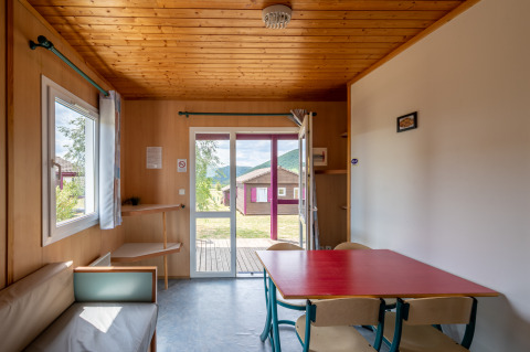 Vista interior del Chalet ZEN en Camping Seasonova Les Vosges du Nord con madera clara y ventanales.