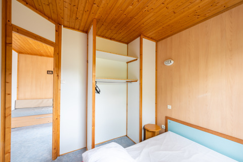 Binnenkant van Chalet ZEN bij Camping Seasonova Les Vosges du Nord met houten plafond en open kast