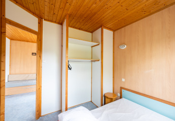 Binnenkant van Chalet ZEN bij Camping Seasonova Les Vosges du Nord met houten plafond en open kast