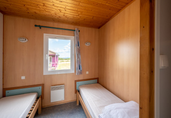 Camera con due letti singoli, interni in legno e finestra, Chalet ZEN a Camping Seasonova Les Vosges du Nord, Francia.