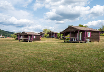 Wooden cabins spread across a grassy field at Chalet ZEN, Camping Seasonova Les Vosges du Nord, France.