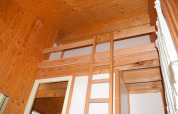 Binnenaanzicht van een houten chalet met slaapzolder en ladder in Chalet Olga op Camping Seasonova Les Vosges du Nord.