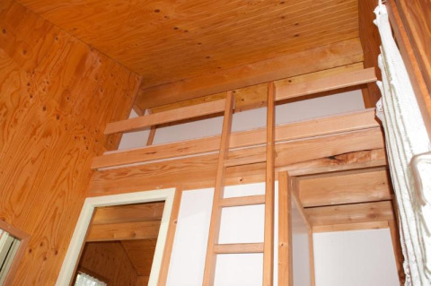 Vista interior de una cabaña de madera con altillo y escalera en Chalet Olga, Camping Seasonova Les Vosges du Nord.